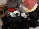 a pile of clothes and a stuffed animal on a bed