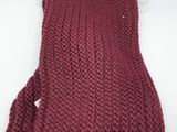 a close up of a red knitted scarf on a white surface
