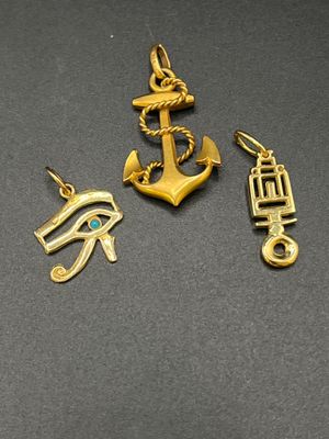trois breloques en or représentant un œil égyptien, un œil d'Horus et un œil d'Horus