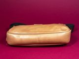 an image of a tan leather bag on a pink background