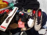 a pile of clothes and shoes on a bed