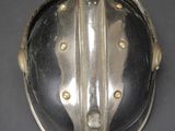 silver plated helmet mounted on a black surface with gold studding