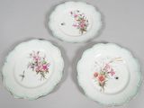 three plates with flowers on them are sitting on a table