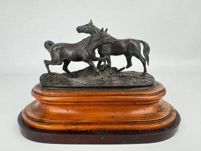 une statue en bronze représentant deux chevaux, posée sur un socle en bois