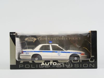 une petite voiture de police dans une boîte, posée sur une surface blanche