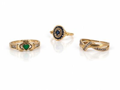 trois bagues en or ornées d'émeraudes et de diamants sur fond blanc