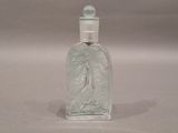a glass bottle with a bird on it sitting on a table