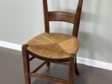 une chaise en bois avec une assise en osier, dans un coin de la pièce