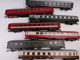 cinq trains posés sur une table blanche : un rouge, un vert et un noir