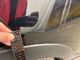 a person holding a ruler that is on the side of a car