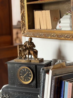 une horloge posée sur le dessus d'une étagère, à côté d'une bibliothèque