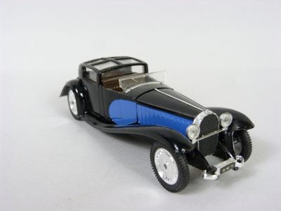 une petite voiture jouet noire et bleue posée sur une surface blanche