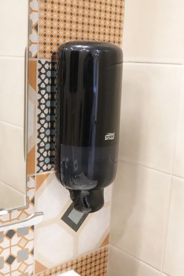 un distributeur de savon noir fixé au mur d'une salle de bains