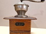 un moulin à café posé sur une table, avec une tasse dessus