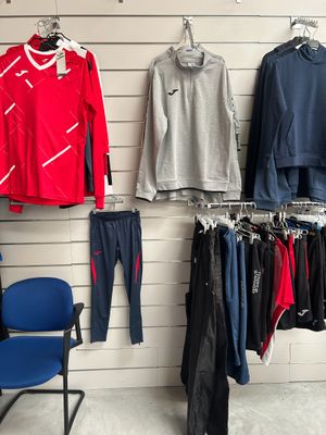 des vêtements suspendus à un mur dans un magasin de vêtements, à côté d'une chaise bleue