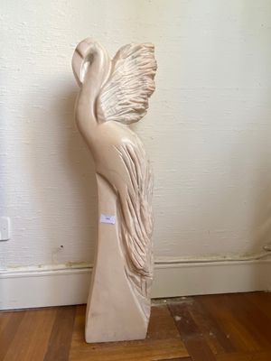 a statue of a bird that is sitting on a wooden stand