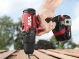 a person using a cordless drill to drill a piece of wood