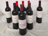 six bottles of red wine are lined up on a bed