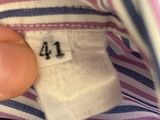someone is holding a button on a striped shirt with a number 41 on it