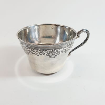 silver plated cup with ornate design on the rim and handle