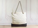 white quilted tote bag with chain handles on wooden floor