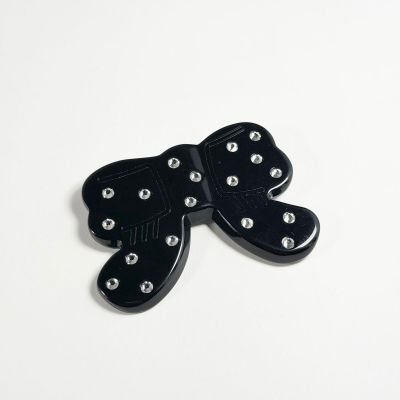 broche en forme de papillon noir avec des clous argentés sur fond blanc