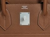 the brown leather handbag has a white button on it