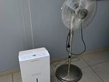 un ventilateur posé à côté d'une boîte blanche sur un sol carrelé