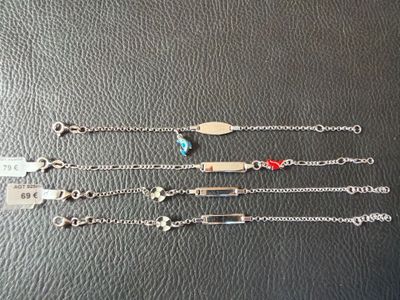 four silver bracelets with different charms on them on a black surface