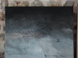 un tableau posé par terre, à côté d'un tableau accroché au mur