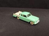 a green toy truck with a flat bed on a black surface