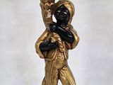figurine dorée et noire représentant un homme tenant une torche