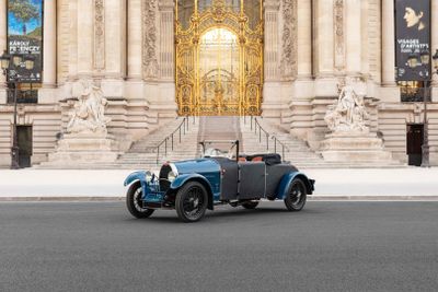 a blue vintage car parked in front of a large building