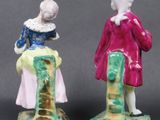 two figurines of a man and a woman standing next to each other