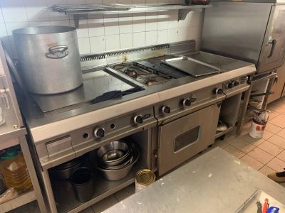 une grande cuisine en inox avec une cuisinière et une casserole posée sur le plan de travail