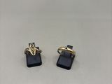 a pair of gold and black earrings on a white surface