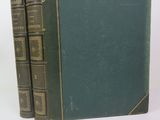 Deux livres verts sont empilés l'un sur l'autre sur une surface blanche