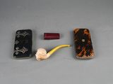 a cell phone, a cigarette, and a cigarette holder on a table