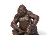 a bronze statue of a monkey sitting on a rock