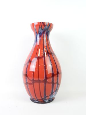a red and blue vase sitting on a white surface
