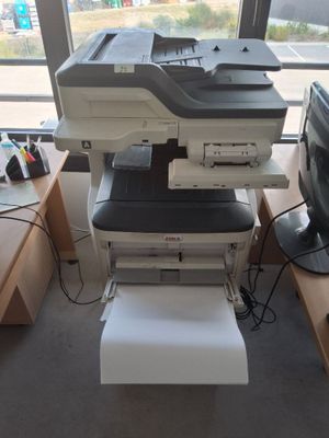 une imprimante posée sur un bureau, à côté d'un écran