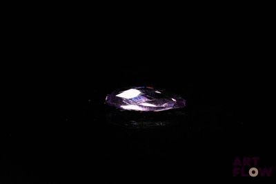 a close up of a purple diamond on a black surface