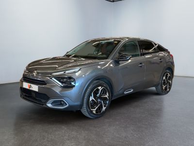 Une voiture grise est garée dans une grande pièce aux murs blancs.
