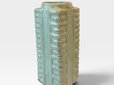 un petit vase posé sur une surface blanche