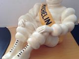 a statue of a man sitting on a desk with a ribbon around his neck