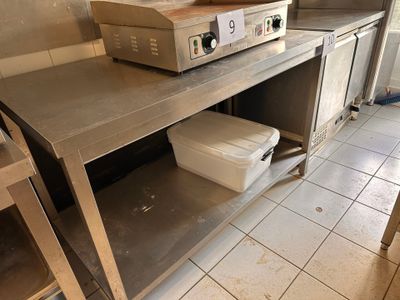 plan de travail en acier inoxydable dans une cuisine professionnelle équipée d'une cuisinière et d'un four