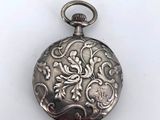 an antique silver pocket watch with a floral design on the front