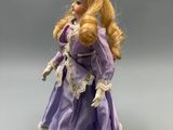 an image of a doll that is wearing a purple dress