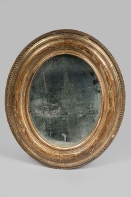 an image of a round mirror with a gold frame on a grey background