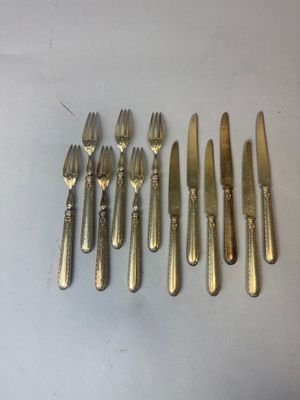 six fourchettes et un couteau sont disposés en rang sur une table